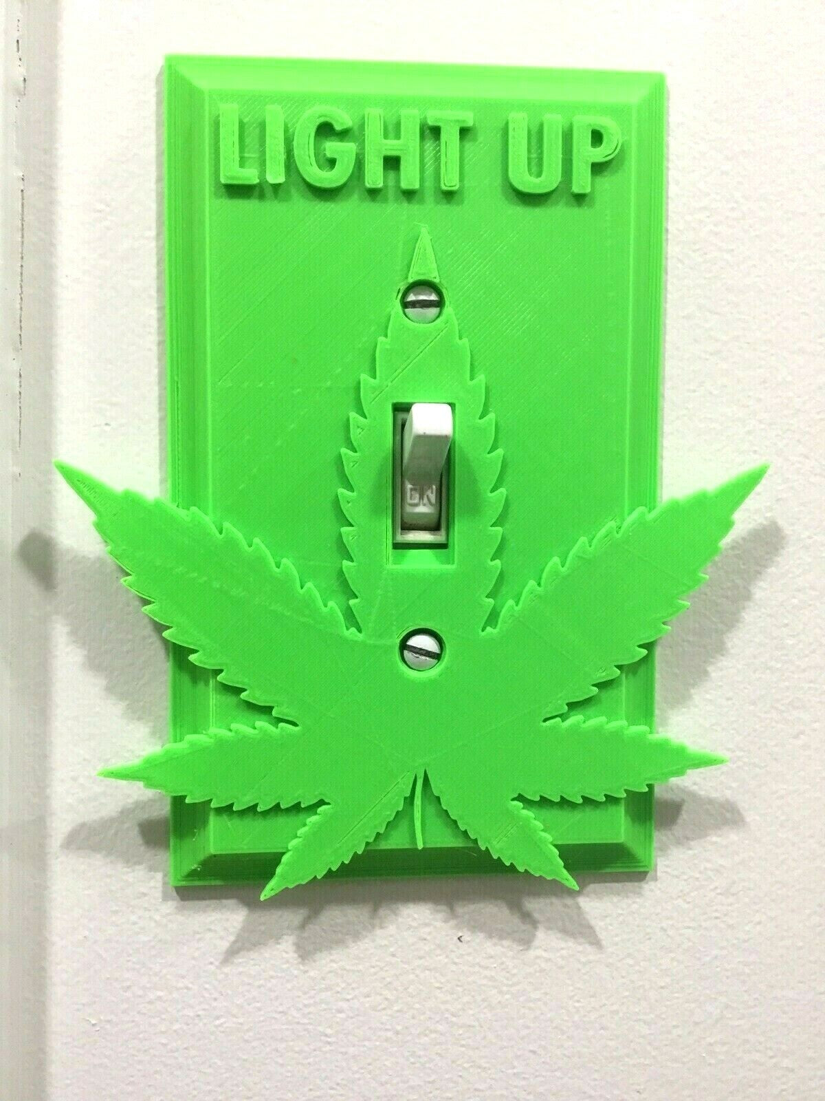 Marijuana-themed light-up switch cover with cannabis leaf design.