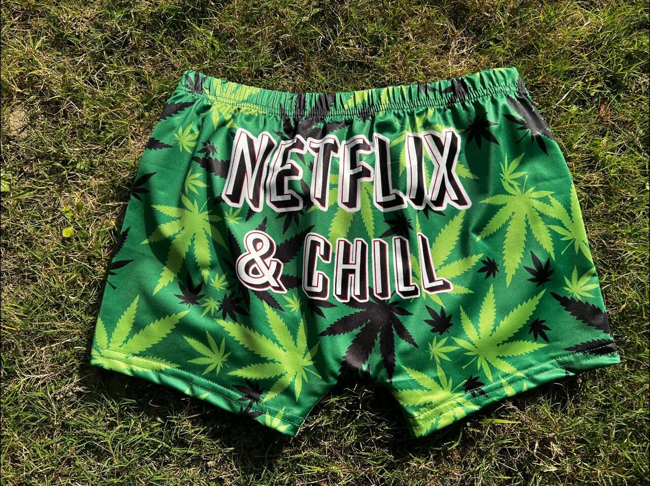 Hemp-themed Chill Weed Yoga Shorts with Netflix & Chill print on grass.