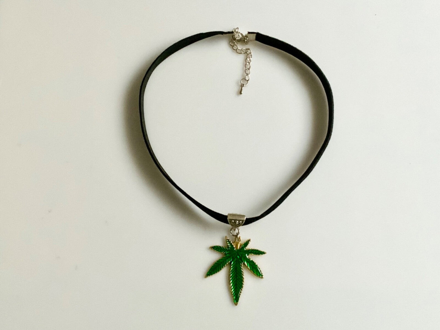 Choker necklace with green marijuana leaf charm on black velvet, custom size.