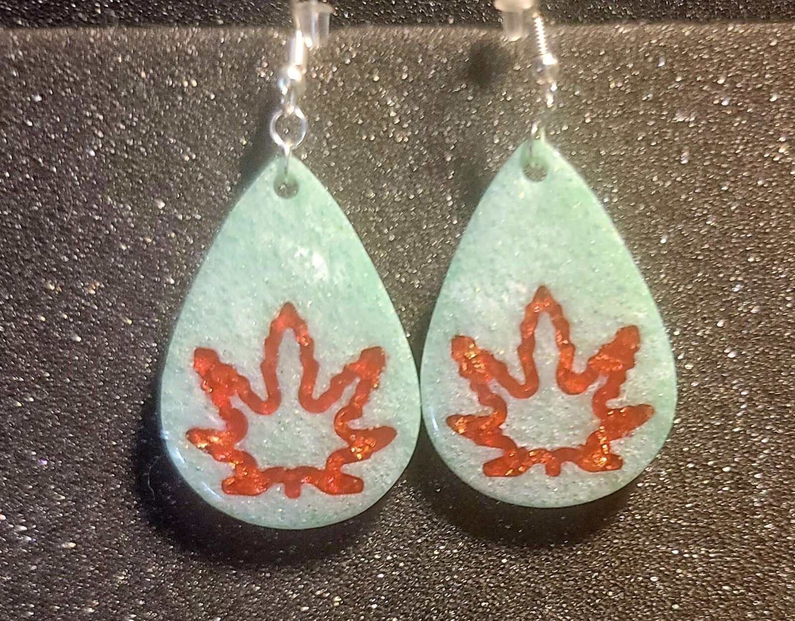 Green dangle earrings with pot leaf design, handcrafted from high-quality materials.