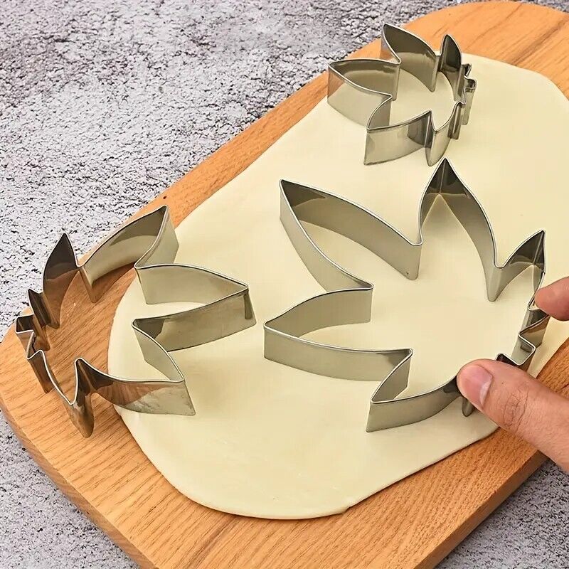 Set of 3 marijuana-shaped silver cookie cutters on dough.