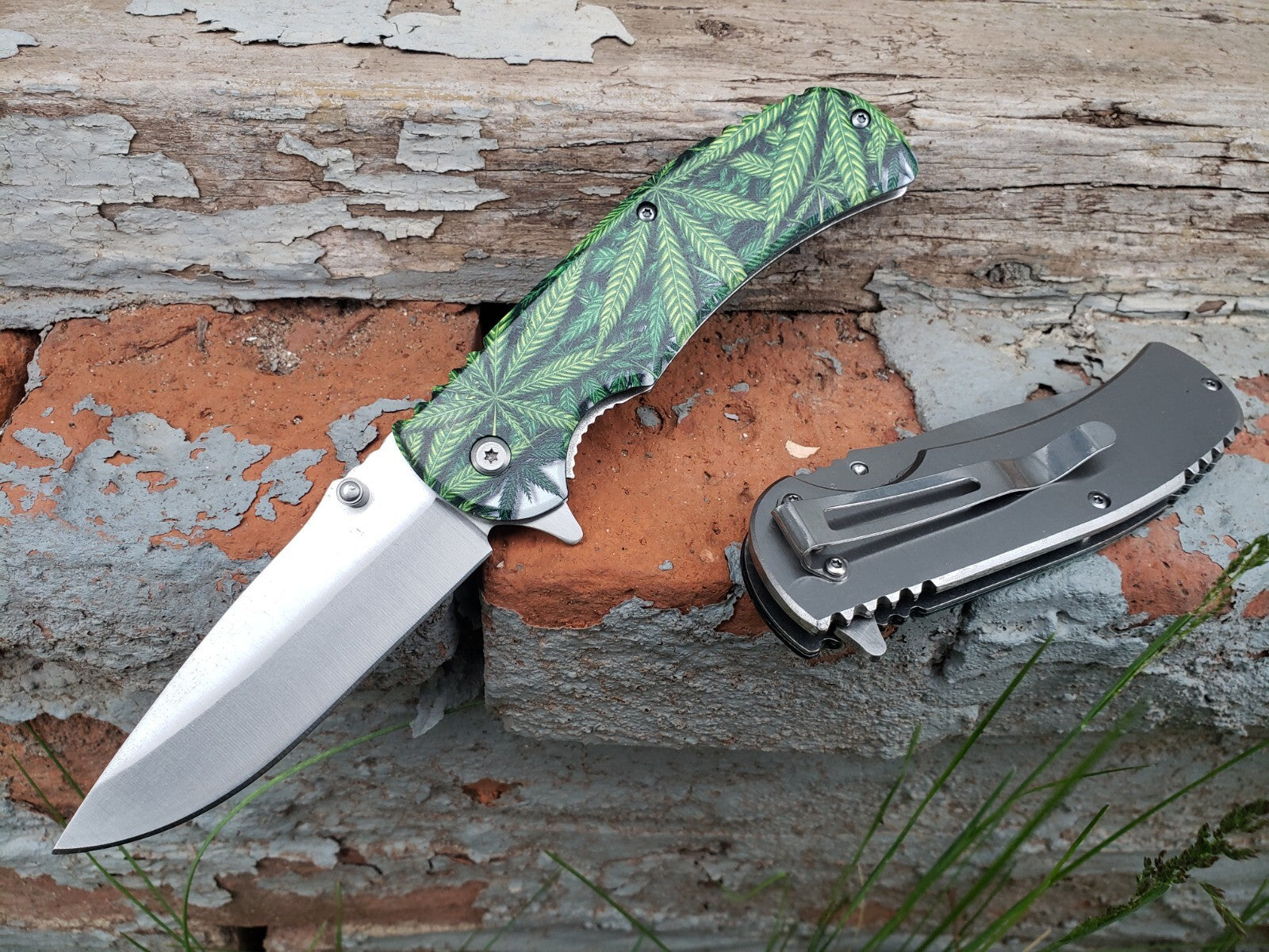Silver green marijuana leaf print spring assisted pocket knife with stainless steel blade.