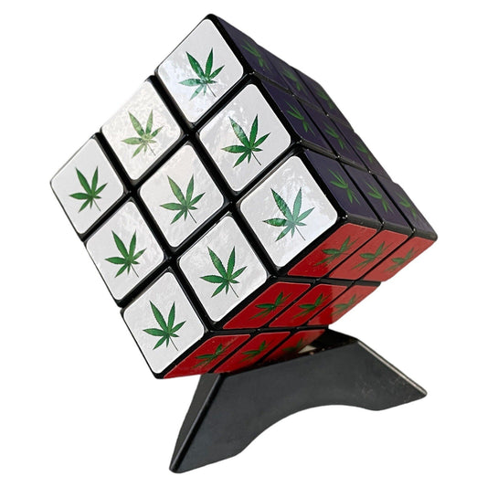 Marijuana themed Rubik's cube with cannabis leaf design on display stand.